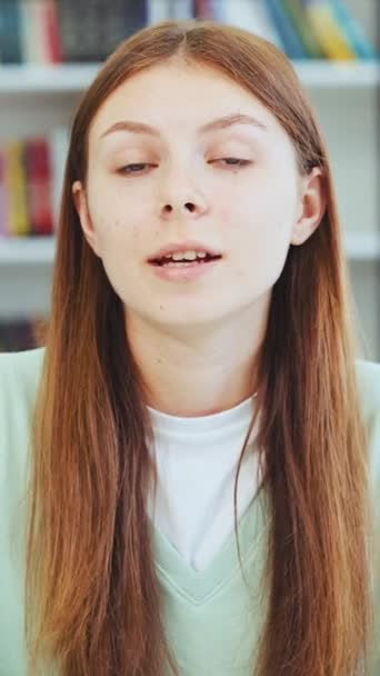 Függőleges Képernyő Tinédzser Lány Integető Kéz Beszél Nézi Kamera Könyvtárban — Stock videók