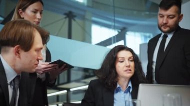 Business team having meeting in office, focus on female CEO talking to managers, checking info on laptop, planning strategy. Concept of buisness