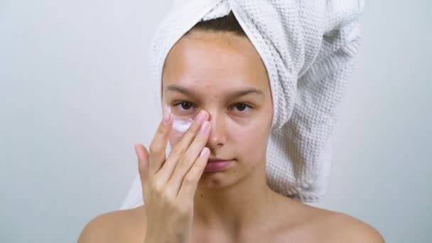 Adolescente Con Toalla Baño Cabeza Mirando Cámara Aplicando Crema Facial — Vídeo de stock