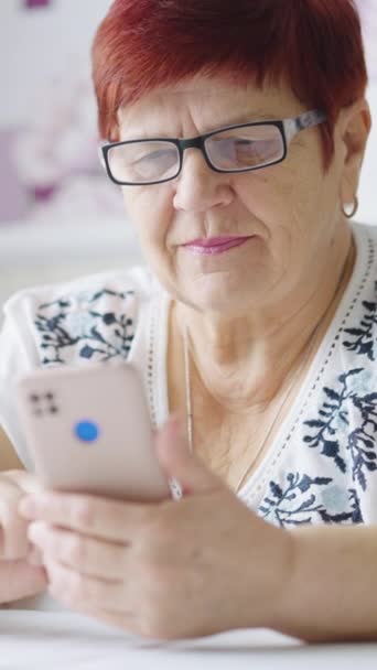 Vertical Screen Senior Woman Wearing Eyeglasses Sitting Table Using Smartphone — Stockvideo
