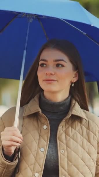 垂直屏风 一个美丽而快乐的年轻女子 带着雨伞在公园里散步 背景模糊的树 休闲的概念 — 图库视频影像
