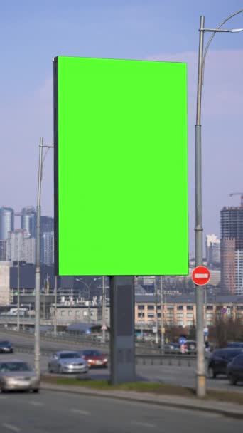 有城市交通背景的绿色大屏幕广告牌 道路上的交通模糊不清 垂直灯箱 用于广告宣传 汽车在城里行驶 — 图库视频影像