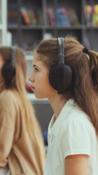 Dikey Ekran Sınıfta Oturan Kızlar Kulaklık Takıyor Duvardaki Cihaza Bakıyor — Stok video