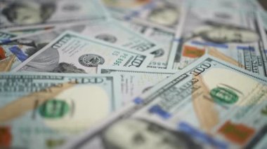 Yüzeyde duran 100 dolarlık banknotlar, seçici odaklanma. Amerikan para birimlerinin çekimleri, para dönen arka planlar. İş kavramı