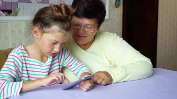 年轻可爱的孙女教奶奶如何在家里使用智能手机 小女孩和老年妇女有闲暇时间在一起 教育理念 — 图库视频影像