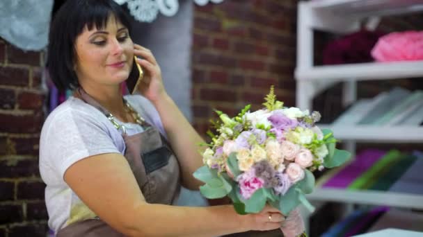 Жіночий Флорист Розмовляє Телефону Обговорюючи Вартість Букета Клієнтом Квітковому Магазині — стокове відео