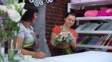 Çiçek tasarım stüdyosunda düğün buketi düzenleyen profesyonel çiçekçiler. Önlüklü beyaz kadınlar çiçek demeti oluşturuyorlar. Çiçek, el yapımı ve küçük işletme konsepti
