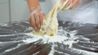 Yakın plan genç kız elleri mutfaktaki karanlık masada hamur yoğuruyor. Sağlıklı gıda, çocukluk, aile, el yapımı, hobi, fırın konsepti