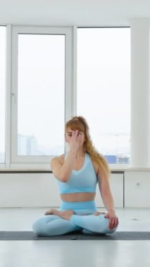 Dikey Ekran: Mavi spor giysili kadın burun ya da burun delikleri egzersizi yapıyor ya da Lotus pozunda nadi shodhana pranayama yapıyor. Yogi kadın, stüdyoda yoga yapıyor. Sağlıklı yaşam tarzını kabul et