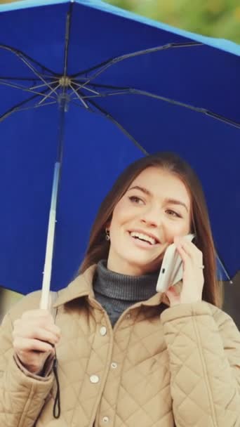 Verticaal Scherm Mooie Jonge Vrouw Met Blauwe Paraplu Aan Telefoon — Stockvideo