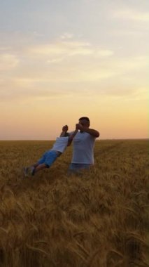 Baba küçük oğlunu elleriyle tutuyor ve buğday tarlasında ağır çekimde dönüyor. Ark neşeli ebeveynleri ve çocukları birlikte harika vakit geçirirken vurdu. Aile kavramı
