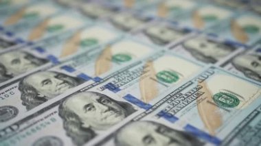 Benjamin Franklin 'in yüzüne odaklanmak için sırayla duran 100 dolarlık banknotların Dolly çekimi. Kamera Amerikan para biriminin yanında hareket ediyor. Maliye ve para ödemesi kavramı