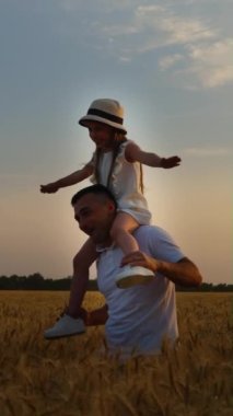 Yavaş çekim baba, omuzlarında küçük bir kızla sahada yürüyor. Çocuğu takip ediyorum, kollarını açıyor, uçakla oynuyor, arka planda mavi gökyüzü var. Aile kavramı