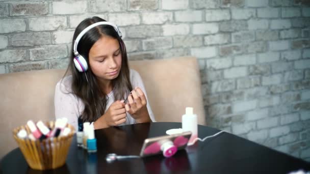 携帯電話で音楽を聞いてヘッドフォンでかわいい女の子 十代の若者は 無料でコピースペースとファイルでマニキュア研磨爪を作ります ボディケア ウェルネス コミュニケーション 余暇時間の概念 — ストック動画