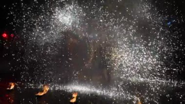 Yavaş çekim tanınmayan ateş gösterisi sanatçısı geceleri havai fişek gösterisi yapıyor, her tarafa kıvılcımlar saçıyor, ön planda alevler yanıyor. Tatil kavramı