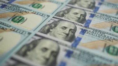 Nakit para dönüyor. Sıraya dizilmiş yüz Amerikan doları Benjamin Franklin 'in portresine odaklanıyor. Banknotlar başarıyı simgeliyor. Maliye ve para ödemesi kavramı