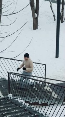 Spor giyimli, metal merdivenlerde koşan ve kameraya yaklaşan, yerde yatan, kar gibi formda bir adam. Yavaş hareket eden sporcu kışın şehir parkında koşuyor. Spor anlayışı