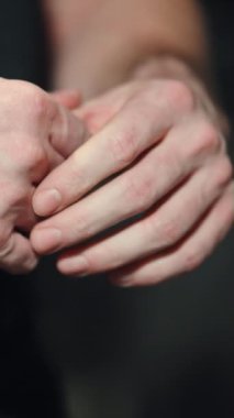 Dikey Ekran: koyu arkaplandaki kaslı adamın elleri. Spor salonunda çalışmadan önce vücut geliştirici ellerini ovuşturup ısıtıyor. Spor anlayışı