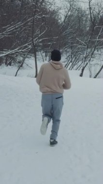 Kar kaplı ormanda spor kıyafetleriyle koşan yavaş çekim adamı. Kışın dışarıda koşu antrenmanının ardından. Sağlıklı bir yaşam tarzı ve açık hava aktivitesi. Spor anlayışı