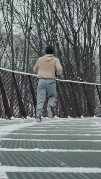 Vertikální Plátno Muž Sportovním Oblečení Běží Zaobleném Kovovém Mostě Zimě — Stock video
