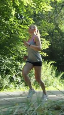 Dikey Ekran: Genç bir kadın açık güneşli bir sabahta doğada koşuya çıkıyor. Atış yapan kadın koşucu dışarıda egzersiz yapıyor. Sağlıklı yaşam tarzı kavramı