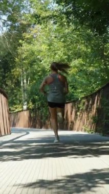 Güneşli bir sabahta spor giyimli bir kadın ağır çekimde metal köprüde koşuyor. Yazın atletizm antrenmanını takip ediyorum. Zindelik kavramı