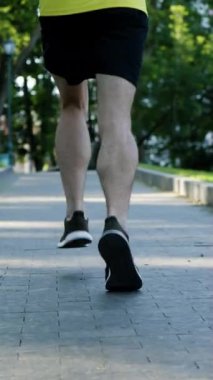 Sunny Park 'ta yürüyüş yolunda koşan erkek bacakları. Sabahları dışarıda ağır çekimde atlet eğitiminin kısmi görüntüsü. Zindelik kavramı