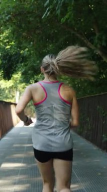 Sabahları spor giyim bölümünde ağır çekimde formda bir kadın metal köprüde koşuyor. Yazın kardiyo antrenmanı yapan bayan sporcu. Zindelik kavramı