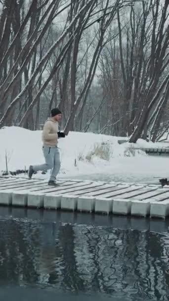 垂直屏风 冬季公园的慢动作男子在桥上慢跑 鸭子在水面上游泳 潘在早上外出锻炼时射中了慢跑者 体育的概念 — 图库视频影像