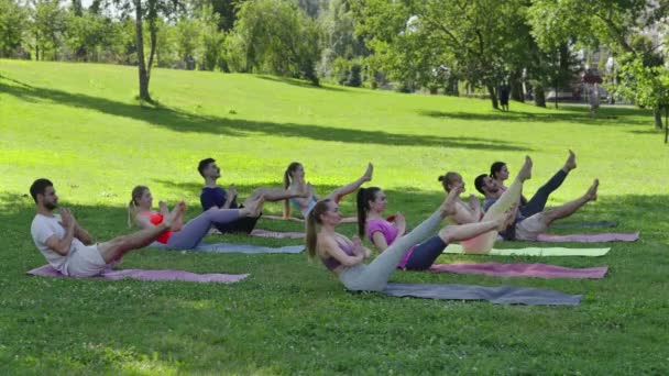 一群年轻的运动健将和教练一起练习瑜伽 在纳瓦萨纳公园进行伸展运动 在城市公园里 不同的团体坐在一起 在小船上保持平衡 健康的生活方式概念 — 图库视频影像