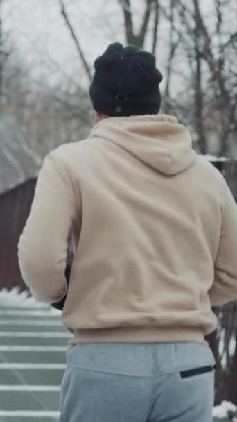 Spor Giyim Şapka Giyen Formda Bir Adam Kışın Metal Köprüde — Stok video