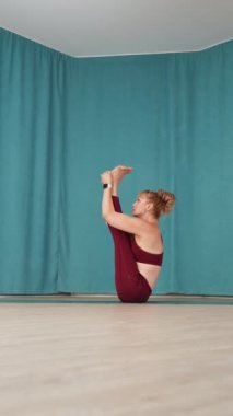 Dikey Ekran: Yoga stüdyosunda Navasana pozu veren formda bir kadın. Bot pozisyonunda oturan Yogi dişisi, oturma kemikleri üzerinde denge kurarak egzersiz yapıyor. Sağlık ve Sıhhat kavramı