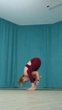 Yandan gören sarışın kadın yoga stüdyosunda geniş bacaklı kıvrım pozu veriyor. Yogi kadın, Prasarita Padottanasana 'yı yapıyor. Sağlık ve Sıhhat kavramı