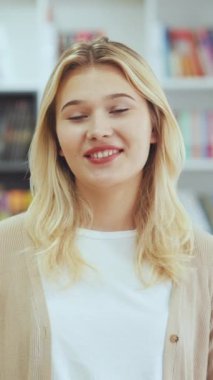 Dikey Ekran: Kadın blogcu etkileyicisi kamerayla konuşuyor, video kaydediyor veya konferans görüşmesi yapıyor. İnternette röportaj veren bir kız. Kütüphanede sunum yapan öğrenci