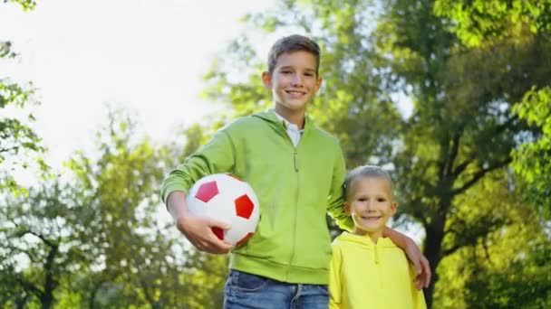 Dva Chlapci Fotbalovým Míčem Dívají Kameru Usmívají Slunečném Parku Nízký — Stock video