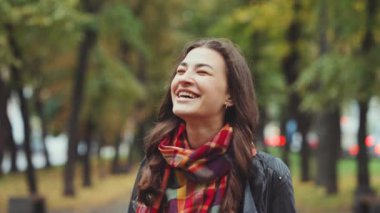 Siyah deri ceketli ve kareli eşarplı güzel ve çekici bir kadın kameraya bakıyor ve sonbahar yollarında bulaşıcı bir şekilde gülmeye başlıyor. Duygu kavramı