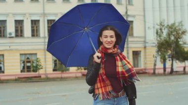 Genç ve çekici bir kadın, kasvetli havaya rağmen, şemsiyesi rüzgarla savruluyor. Yalnız bir kadın rüzgarlı havada bekliyor..