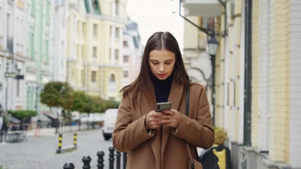 Νεαρή Γυναίκα Φορώντας Καφέ Παλτό Προσεκτικά Πληκτρολογώντας Μήνυμα Στο Κινητό — Αρχείο Βίντεο