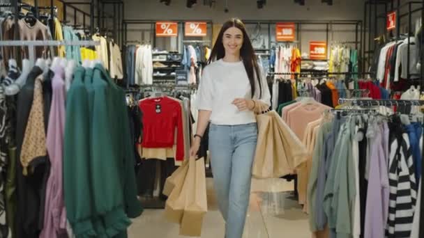 Femeie Tânără Satisfăcută Cumpărăturile Pungi Hârtie Care Părăsesc Magazinul Îmbrăcăminte — Videoclip de stoc