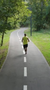 Spor giyim sektöründe formda bir adam ağır çekimde işaretleme ve yeşil ağaçlarla yolda koşuyor. Park 'ta antrenman yapan bir atleti takip ediyorum. Zindelik kavramı