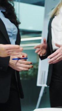 Dikey ekran: İş ortaklarının ofiste el sıkışırken kısmi görünümü, arka planda bayan meslektaşlar. Üst düzey yöneticiler anlaşmaya varıp anlaşma yapıyorlar. Başarı kavramı