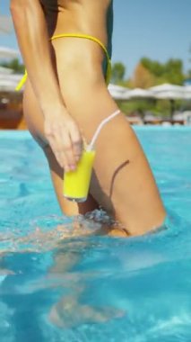 Sarı bikinili ince bir kadın elinde meyve suyu olan bir havuza giriyor. Otelde dinlenen büyüleyici bir kadın. Yaz tatili ya da tatil