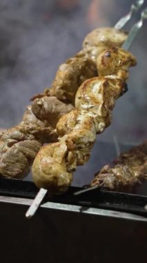 Kömür ızgarasında kızaran et şişleri, siyah üniformalı ve eldivenli adamlar arkada durup hazır olup olmadıklarını kontrol ediyorlar. Sokak fuarında yemek pişirmeye yakın. Yiyecek kavramı