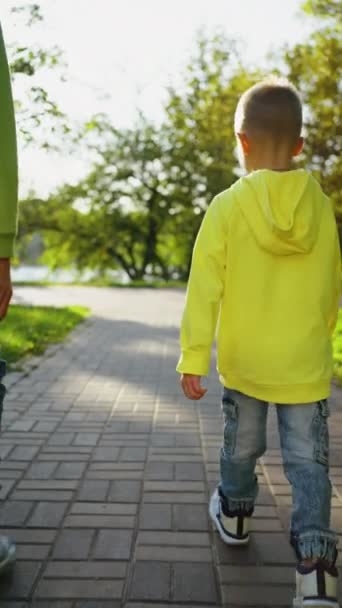 Pionowy Ekran Widok Tyłu Dwóch Chłopców Spacerujących Parku Młodszy Wyciągnął — Wideo stockowe