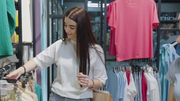 Две Женщины Выбирают Одежду Магазине Одежды Одна Женщина Длинными Волосами — стоковое видео