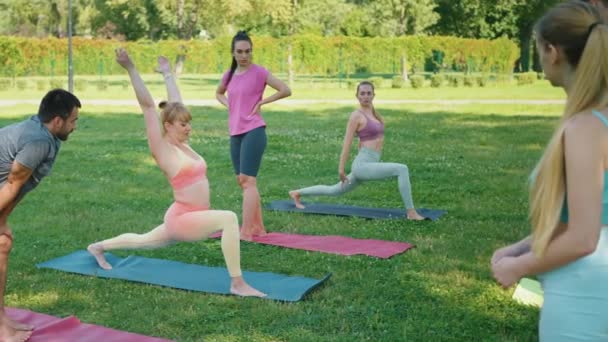 Yoga Instructor Demonstrates Lunge Pose Guiding Participants Practice Vibrant Park — Stock Video