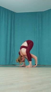 Dikey ekran: Kadın yogi ustalarının dengesi, kapalı bir yoga stüdyosunda bacaklarını ileri uzatarak amuda kalkıyor