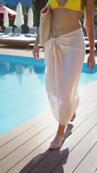 縦スクリーン 結ばれたラップが付いている黄色い水着の木のプールのデッキの裸足を歩く認識できない女性 夏休みや休日について — ストック動画