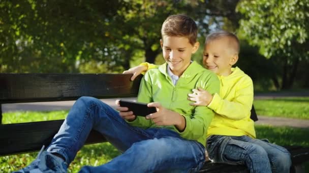 Oudere Broer Verdiept Een Spel Een Smartphone Met Zijn Jongere — Stockvideo
