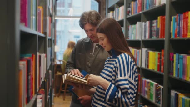Dois Estudantes Envoltos Livro Leitura Juntos Entre Prateleiras Coloridas Biblioteca — Vídeo de Stock